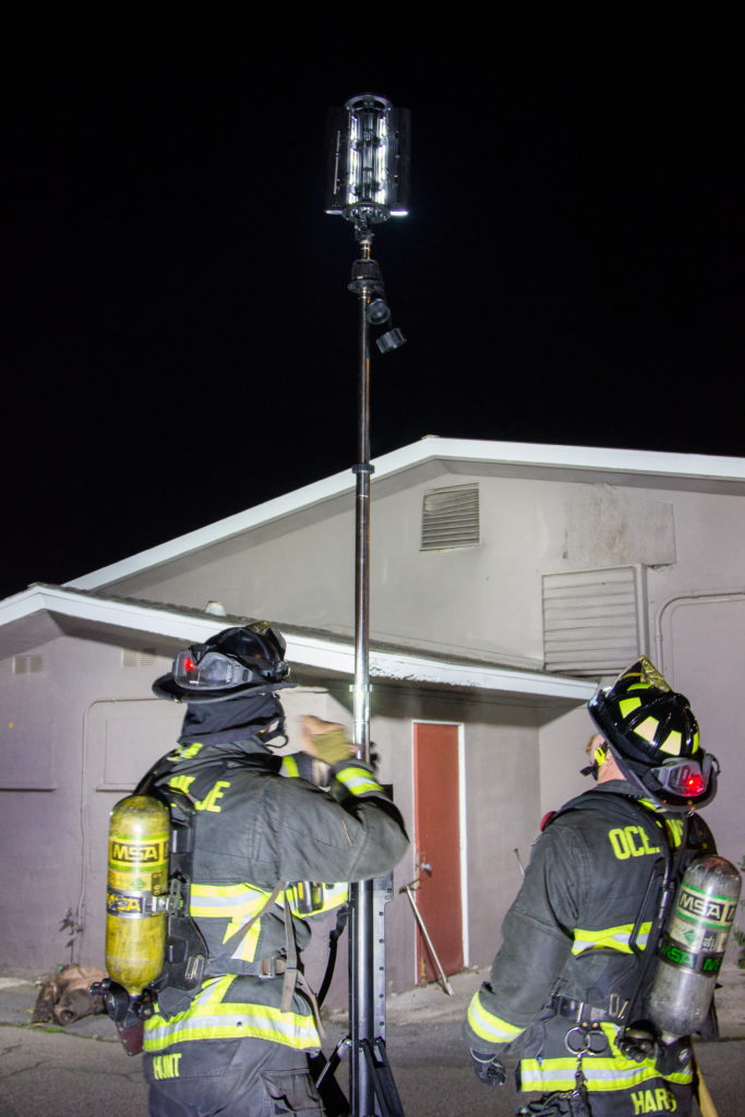 Two firefighters set up a FoxFury Nomad Transformer scene light