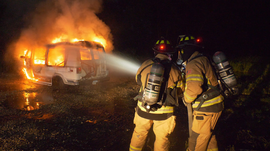 Firefighters with FoxFury Command and Discover helmet lights extinguish a vehicle fire