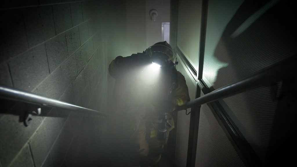 Firefighter with FoxFury Discover headlamp climbs stairs