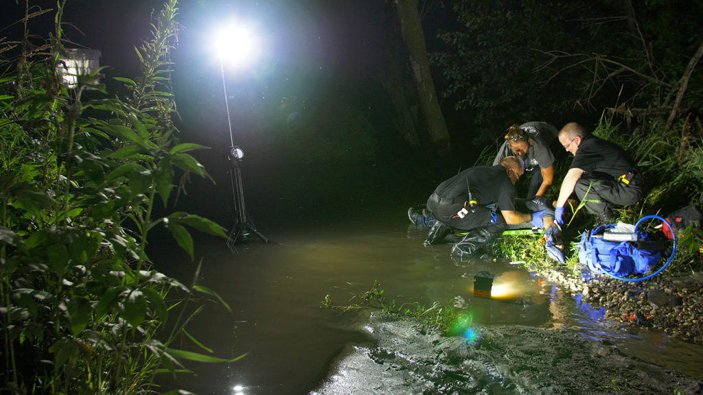 Waterproof FoxFury Nomad lights are staged in a stream to illuminate a EMTs treating a victim