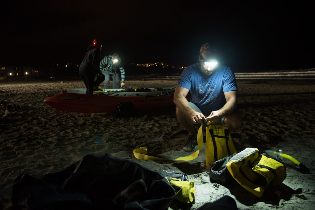 Kayaker wears FoxFury Command headlamp while packing dry bags at night