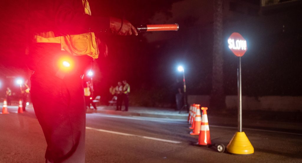 Police officer wearing a Scout Clip Light with White and Red LEDs at traffic checkpoint